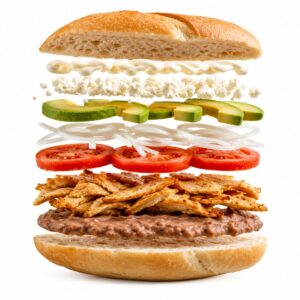 Torta artesanal con ingredientes flotando: bolillo, frijoles, milanesa de pollo o res, jitomate, cebolla blanca, aguacate, queso blanco y mayonesa sobre fondo blanco.