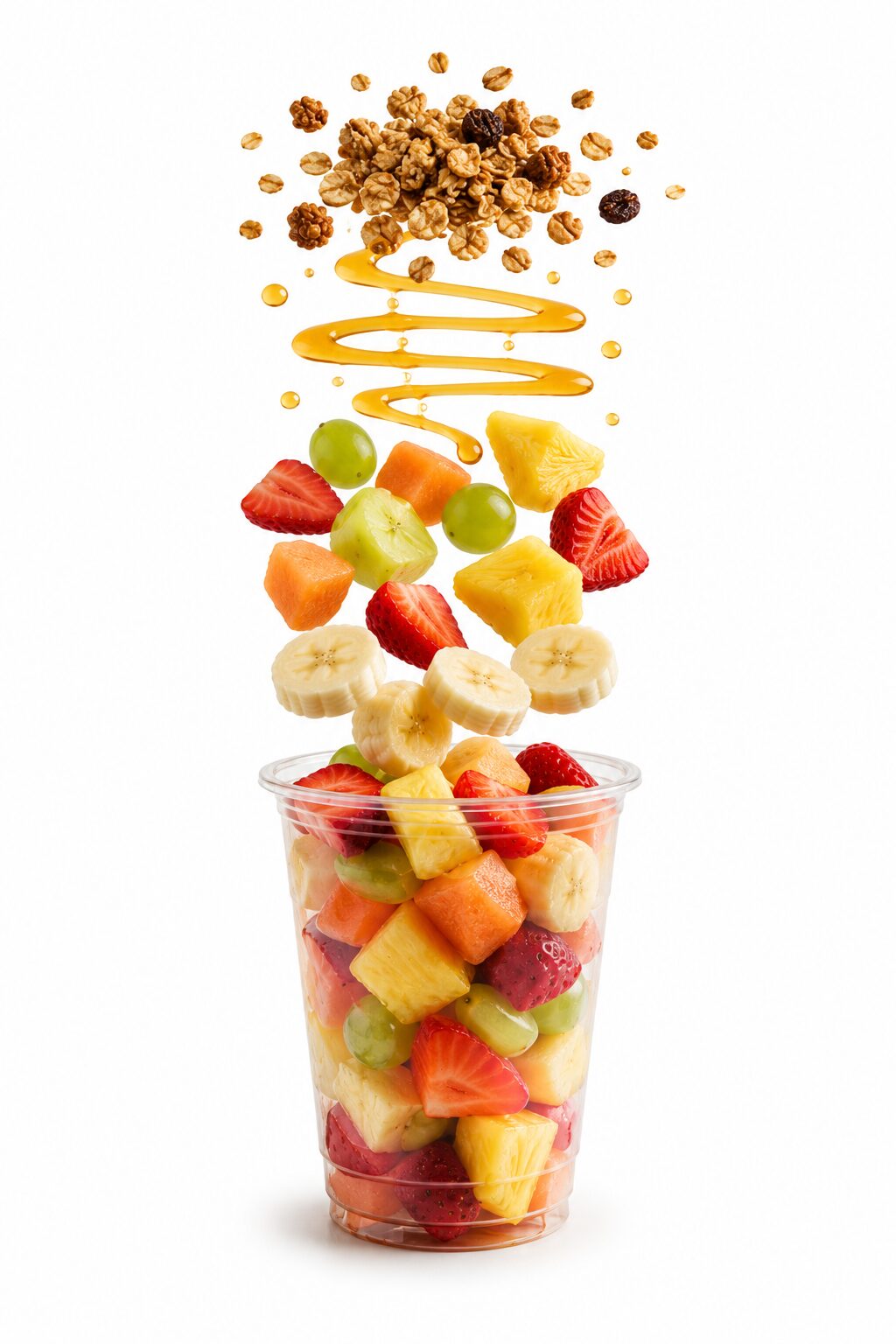 Vaso de fruta fresca con ingredientes flotando: frutas variadas, miel y granola sobre un vaso transparente con fondo blanco.